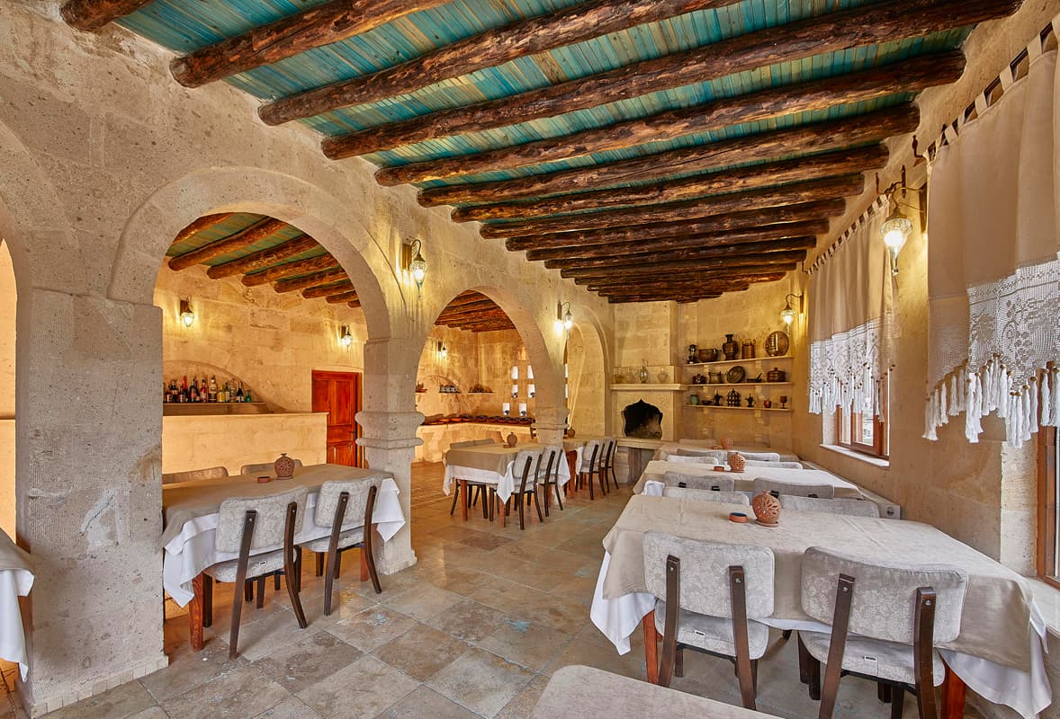 Ahşap kirişli tavanlı, taş kemerli restoran salonu